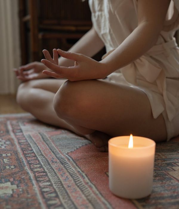 Woman in a peaceful yoga pose, bathed in fuchsia light.